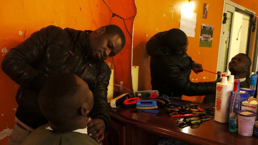 Kelvin Karim trims Victor's beard [Sean O'Neill/Al Jazeera]