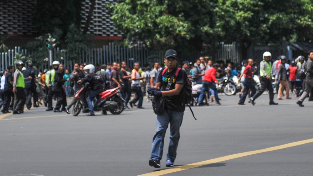A man is seen holding a gun as people run away in central Jakarta, Indonesia [Reuters]