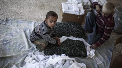 Young Syrians rolling gauze to be packaged and distributed for use after being manufactured at a small local factory run by the Union of Free Syrian Doctors, in rebel -held Douma, on the outskirts of Damascus, December 2015. [EPA]