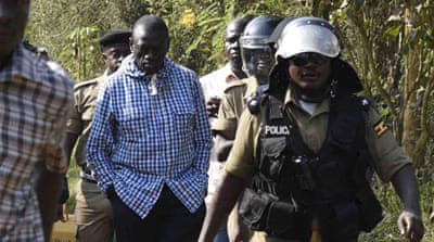 Opposition leader Kizza Besigye is escorted by Ugandan policemen to a police vehicle outside his house at the outskirts of Kampala [Reuters]