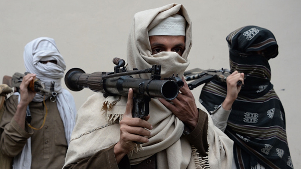 Former Afghan Taliban fighters carry their weapons before handing them over as part of a government peace and reconciliation process at a ceremony in Nangarhar province [AFP]