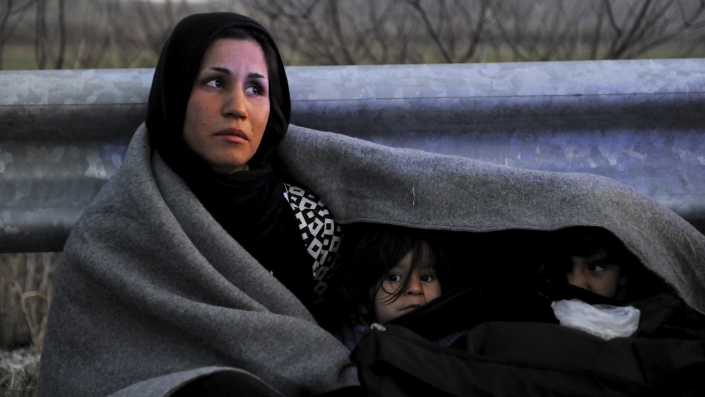 An Afghan mother covers herself and her children with a blanket while trying to reach the Greek-Macedonian border, following reports that Macedonia has closed its borders with Greece to Afghan migran