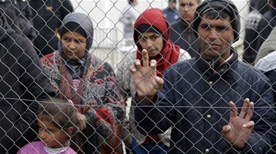 Migrants and refugees stand by a fence at a makeshift camp at the Greek-Macedonian border near the village of Idomeni, Greece [Reuters]