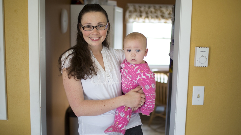 Lindsay Pappas poses for a portrait with her eight-month-old son, Gus. Pappas and her husband are both graduate students at Indiana University and have four children [James Brosher/Al Jazeera] 