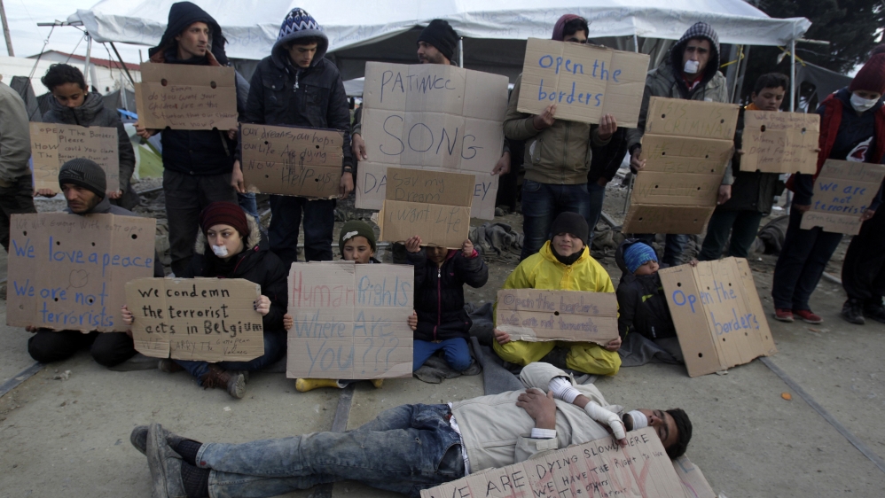 A refugee performs as others hold placards during a protest in a makeshift camp for refugees and migrants at the Greek-Macedonian border near Idomeni [Alexandros Avramidis/Reuters]