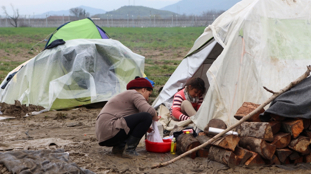 A woman washes clothes outside her tent [John Psaropoulos/Al Jazeera]