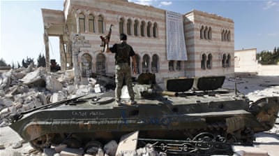A Free Syrian Army rebel fighter stands on a damaged Syrian military tank in front of a mosque, destroyed during fighting with government forces in the Syrian town of Azaz [AP]