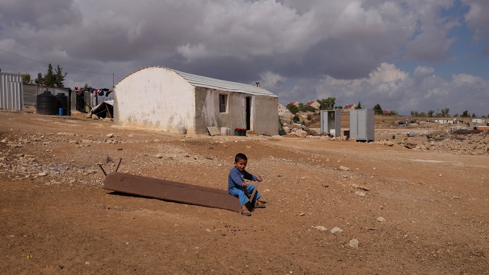 Suleiman Hathaleen's grandchild plays on a discarded trough. On April 6, 35 people were made homeless when Israeli authorities demolished six structures in Umm el-Khair [Dalia Hatuqa/Al Jazeera]