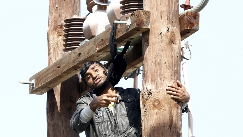 Pakistani migrant threatens to hang himself from a utility pole during a demonstration inside the Moria registration centre on the Greek island of Lesbos