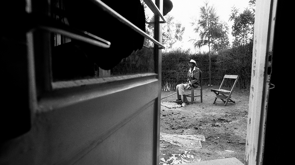A deeply traumatised old man sits alone in the yard of his home in Rukara [Jack Picone/Al Jazeera]