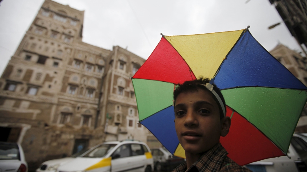 A boy with an umbrella hat walks in an old quarter of Yemen''s capital Sanaa [REUTERS]