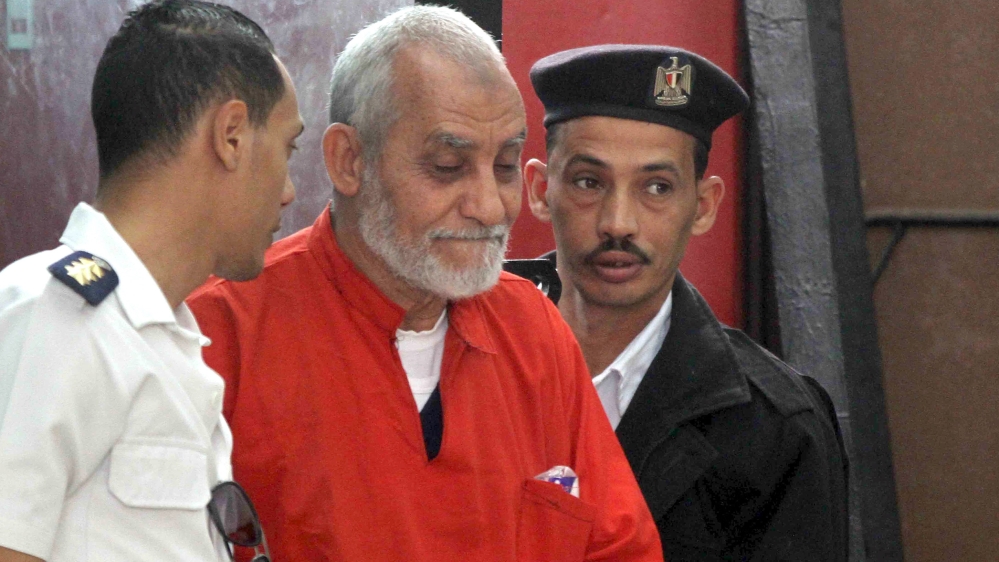 Mohamed Badie, top leader of Egypt''s outlawed Muslim Brotherhood, is led by police to talk during a trial hearing alleging his involvement in a 2013 attack on a Port Said police station at a court