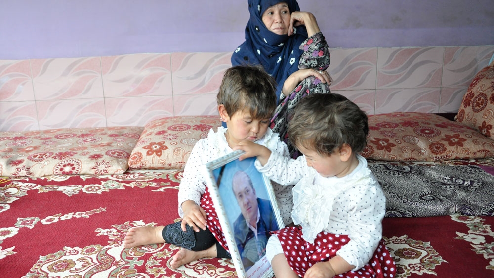 Sitaeesh, left, smiles at her late father's picture [Fatima Faizi/ Al Jazeera]
