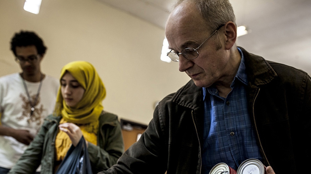 The Rev Bob Pounder, minister at the chapel, stacks donated tins of food at UKEFF's food bank [David Shaw/Al Jazeera]