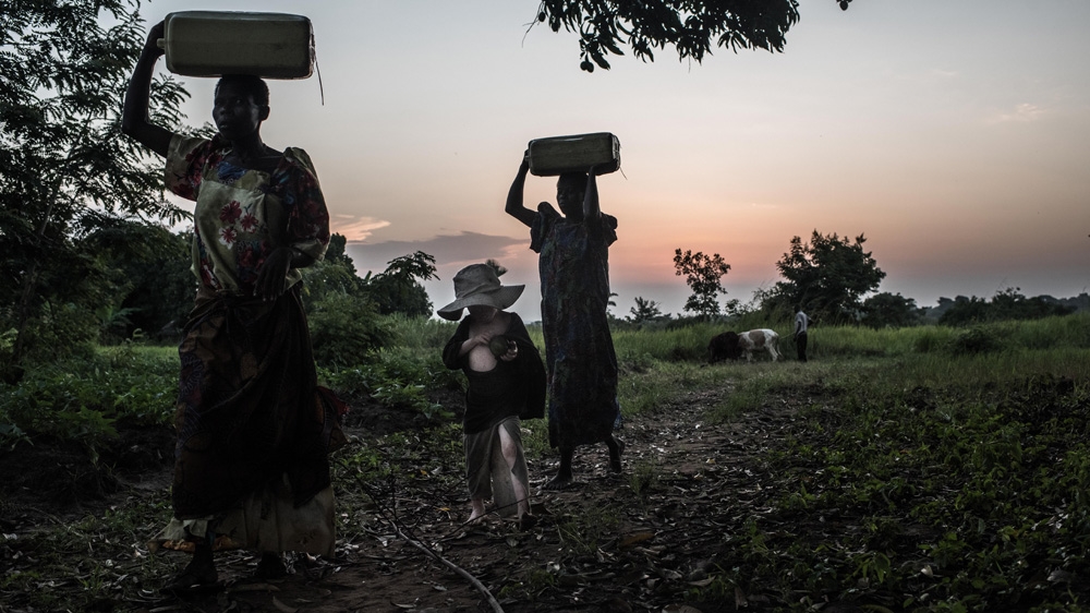 Florence and Lynda fetch water before dinner. They are joined by Mwanje Bernard in the middle [Fredrik Lerneryd/Al Jazeera]