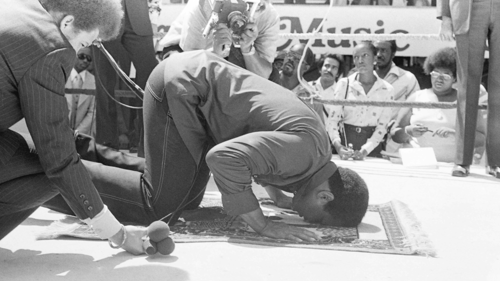 Muhammad Ali prays at a press conference before his fight against Ken Norton [File: August 4, 1976 - The Ring Magazine/Getty Images]