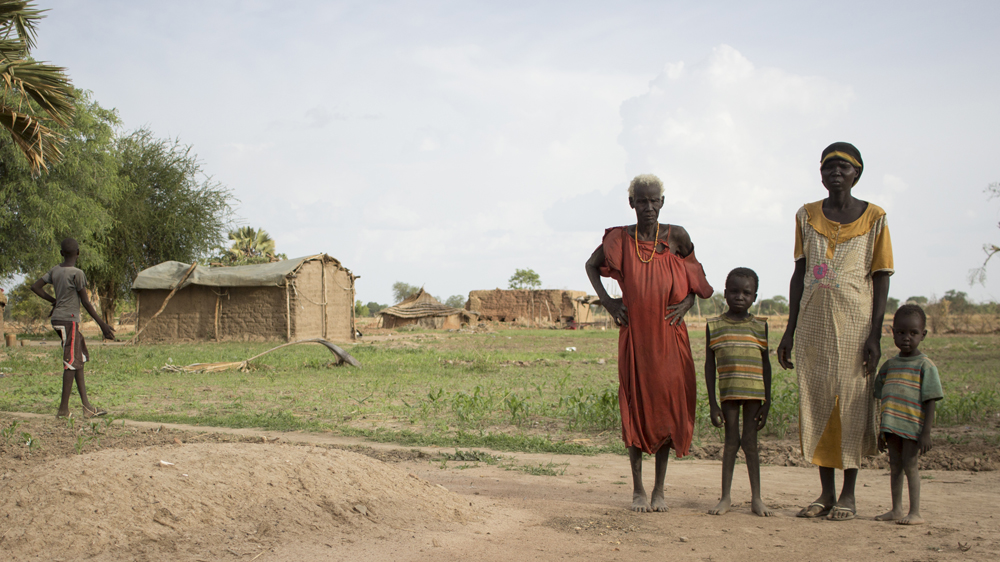 A family from Kanjak stand by the grave of a family member who died from not having enough to eat [Henry Wilkins/Al Jazeera]