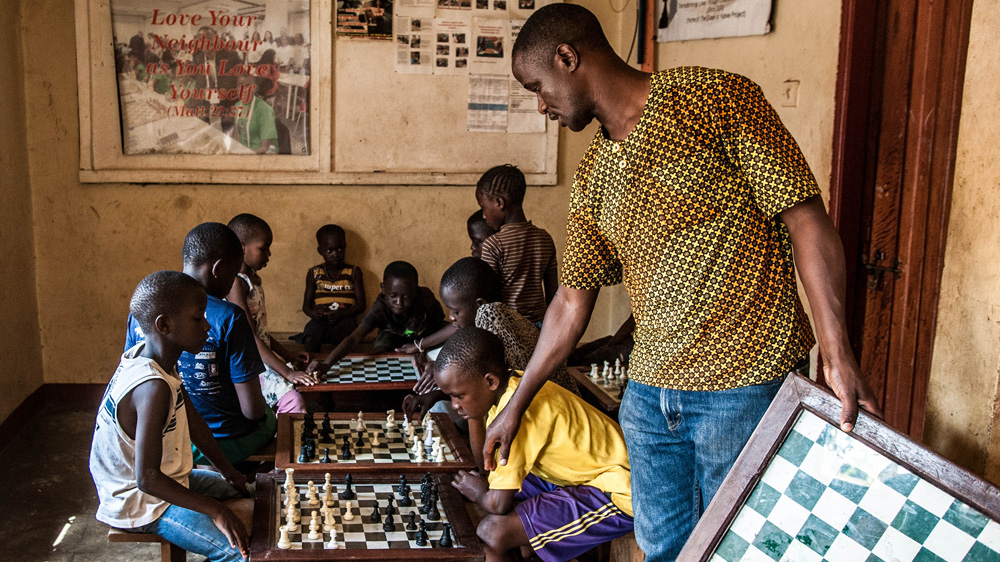 Katende advises one of his students during a match at the Katwe Chess Academy