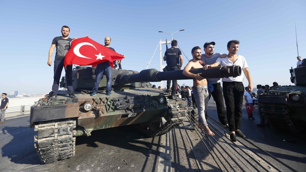 People pose near a tank after troops involved in the coup surrendered on the Bosphorus Bridge in Istanbul