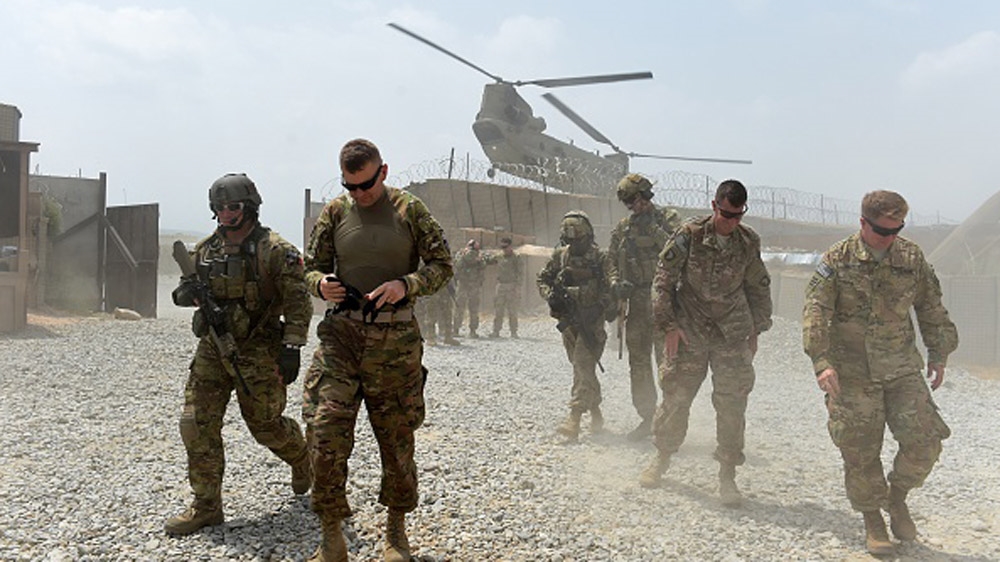 US army soldiers walk as a NATO helicopter flies overhead at coalition base in the eastern province of Nangarhar [Getty]