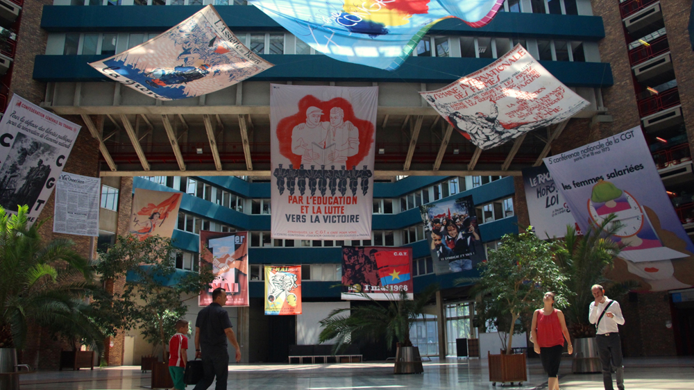 A banner reading 'Through education and struggle, towards victory' floats above the entrance to the General Confederation of Labour headquarters in Paris [Paul Fargues/Al Jazeera]