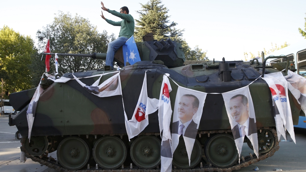 A man poses on an Armored Vehicle with portraits of Turkish President Tayyip Erdogan parked outside the parliament building in Ankara