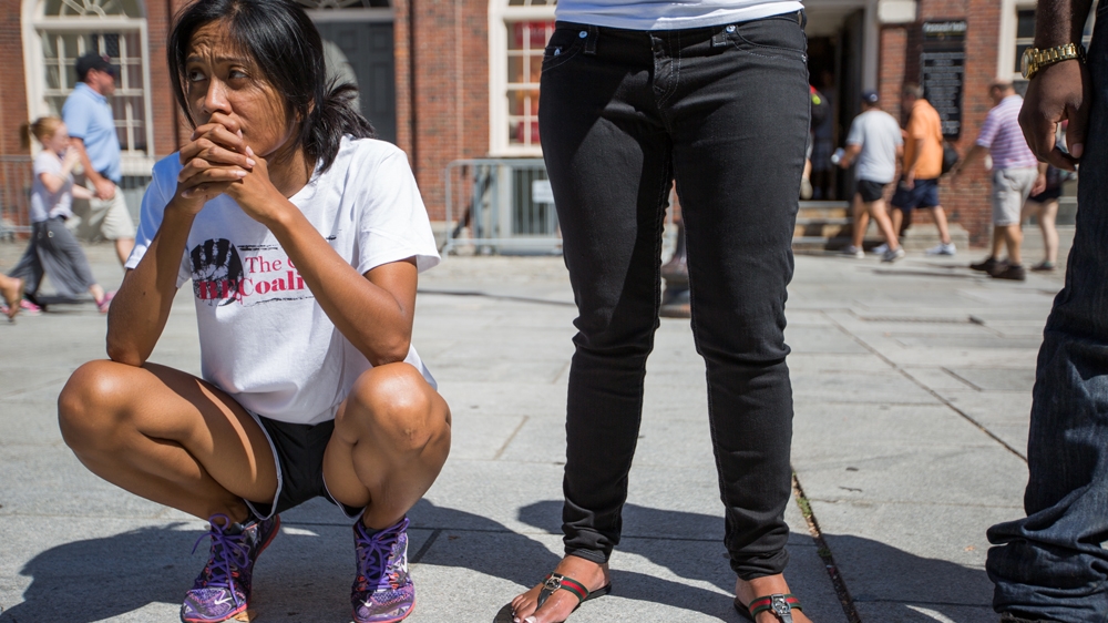 Marie Nuon, left, listens to Nia Evans speak outside Faneuil Hall [Carolyn Bick/Al Jazeera] 