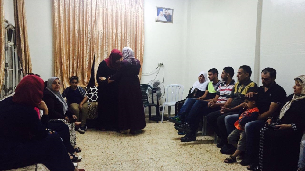 Sada's family welcomes her home, as a photo of her jailed brother hangs on the wall [Photo courtesy of Palestinian Prisoner's Centre for Studies]