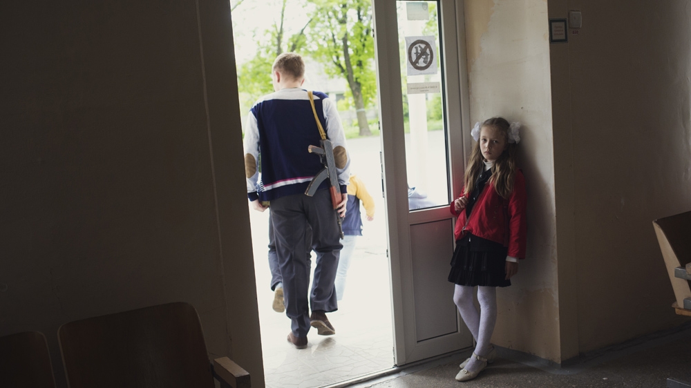 One of the oldest students at School No 58 makes his way to military training carrying a replica weapon. Later, they will practise with the real thing [Kyrre Lien /Al Jazeera] 