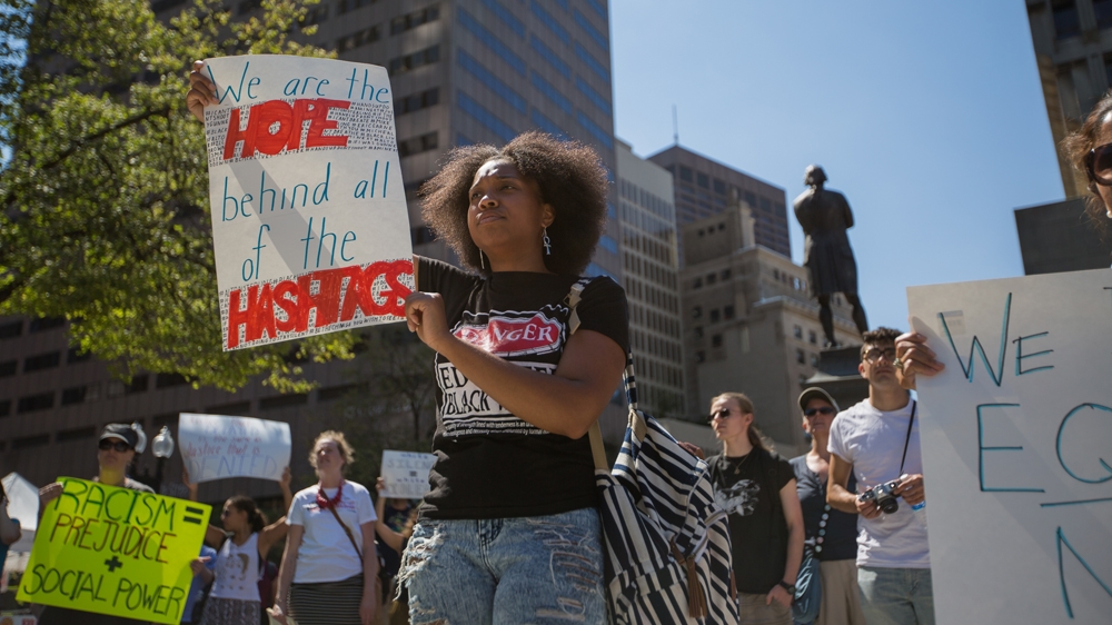 Shalece Perryman-Welch holds up a sign that reads, 'We are the hope behind all of the hashtags,' outside Faneuil Hall [Carolyn Bick/Al Jazeera] 