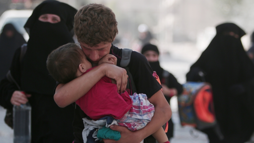 A civilian carries a child as he walks with others after they were evacuated by the Syria Democratic Forces (SDF) fighters from an Islamic State-controlled neighbourhood of Manbij