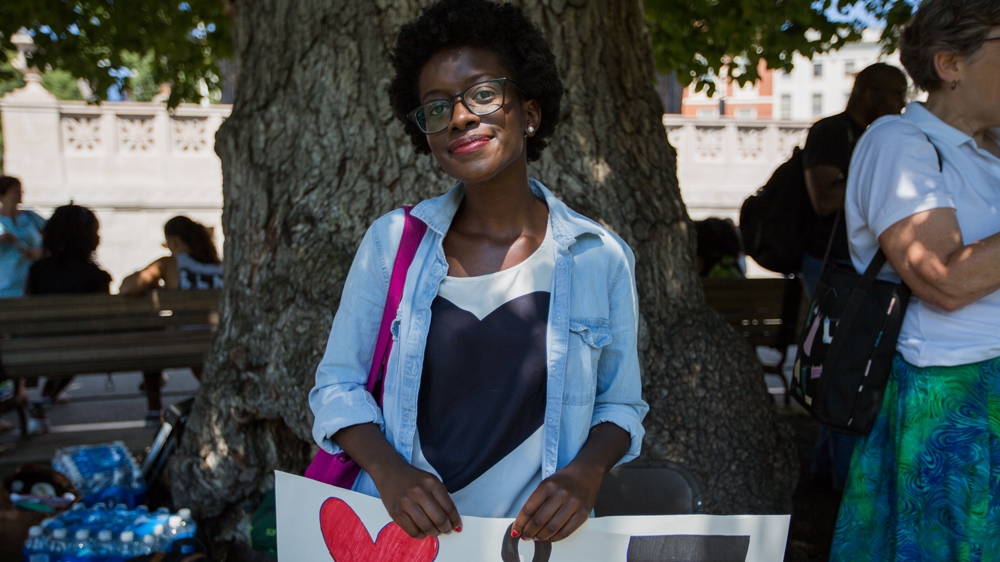 Barbara Okeny poses for a photograph as she waits for the Coalition's rally to begin [Carolyn Bick/Al Jazeera] 