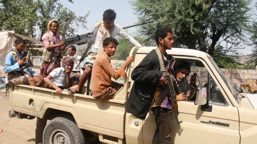 Pro-government fighters ride on the back of a truck at al-Dhabab area after they took it from Houthi fighters outside the southwestern city of Taiz, Yemen