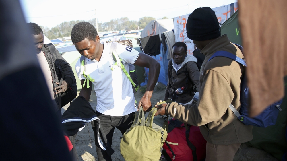 A migrant carries his belongings as he walks past t