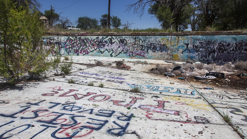 Works Progress Administration Pool. At its prime, this was the largest outdoor pool in New Mexico [Gabriela Campos/Al Jazeera]A collection of vintage cars parked outside the concrete Wigwams in Holbrook, Arizona [Gabriela Campos/Al Jazeera]Tourists stop to partake in one of the many odd attractions along Route 66 [Gabriela Campos/Al Jazeera]Dinosaurs and teepees are a recurring theme along historic Route 66 used to attract motorists into the roadside shops [Gabriela Campos/Al Jazeera]An abandoned playground in eastern Arizona [Gabriela Campos/Al Jazeera]An obscured Route 66 sign at an old hotel in eastern Arizona [Gabriela Campos/Al Jazeera]The neon lights of one the remaining Indian curios stores in Tucumcari, New Mexico [Gabriela Campos/Al Jazeera]John Lewis, owner of the Wigwam Motel, sitting in the hotel lobby [Gabriela Campos/Al Jazeera]Tattered curtains in a window of one of the many vacant motels along the old highway [Gabriela Campos/Al Jazeera]An old suitcase left by a Route 66 traveller [Gabriela Campos/Al Jazeera]The keys to the rooms of the Paradise Motel sit idly on their hooks, waiting for guests that once came and went, many years ago [Gabriela Campos/Al Jazeera]One of the many abandoned food and lodging venues along Route 66 [Gabriela Campos/Al Jazeera]