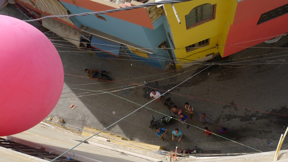 Participants watch from below as the red balloon sails above a spot in the camp [Courtesy of Greening Bourj al-Shamali] 