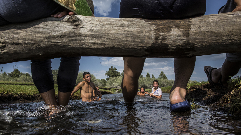 A herding family plays in a stream in Ikh Tamir. Participating in a PUG has let herders reap greater financial returns through collective negotiations to get higher prices [Taylor Weidman/Al Jazeera