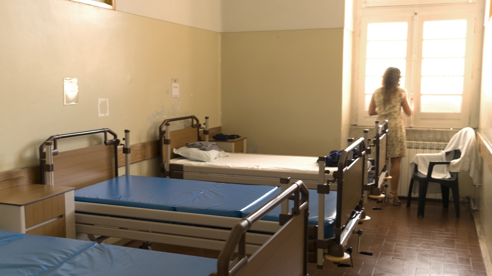 Dr Rosa Castro Andre in a dormitory at Taipas. Sheets are cleaned every night as patients come straight from the streets [Eline van Nes/Al Jazeera]