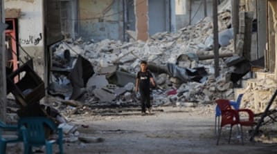 A boy walks past damaged buildings in the northern Syrian rebel-held town of al-Waqf, in Aleppo [REUTERS]