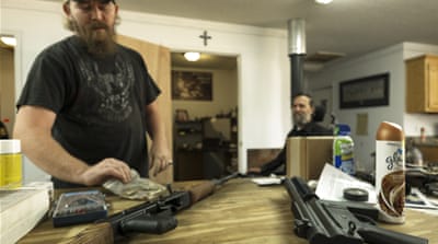 Qualls and Schmitt show different kinds of rifles [Eline van Nes/Al Jazeera]