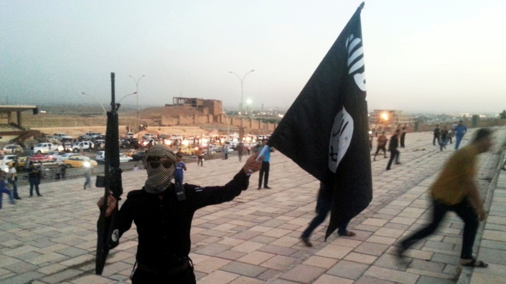 ISIL fighter holds a flag and a weapon on a street in Mosul