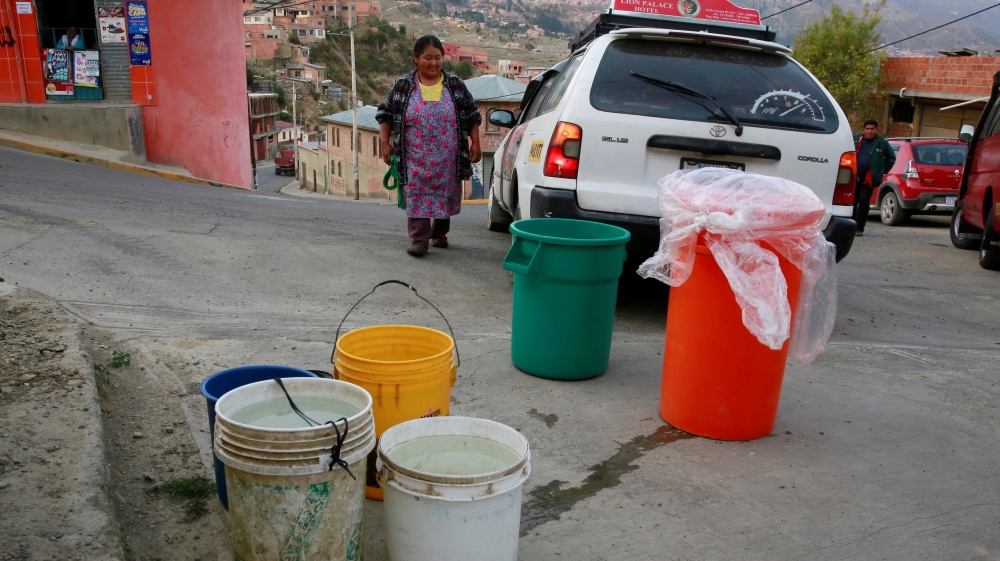 A woman prepares to load a car with buckets of water in Kupini, La Paz
