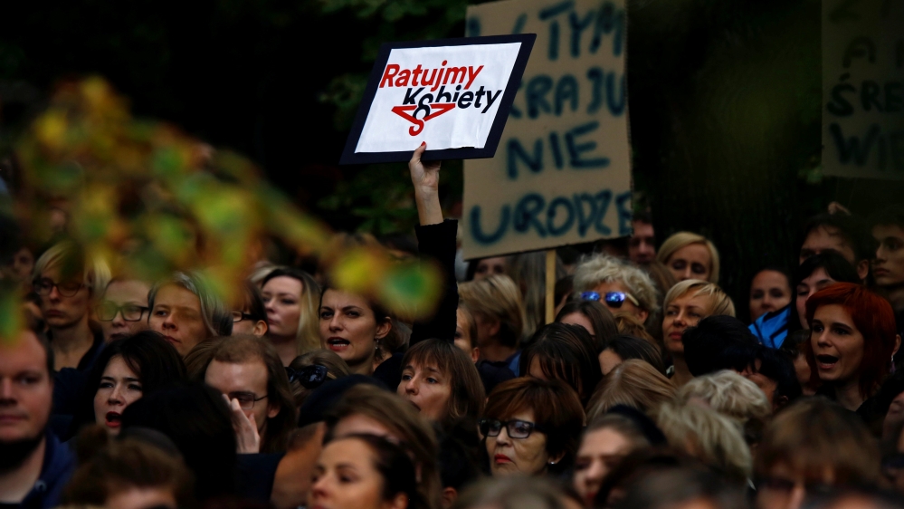 Woman hol placard reading "Let''s save women" as she takes part in abortion rights campaigners'' demonstration "Black Protest" in front of the Parliament in Warsaw