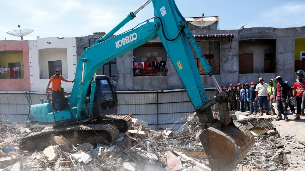 Rescue teams use heavy equipment to dig through a collapsed building following a strong earthquake [Darren Whiteside/Reuters]