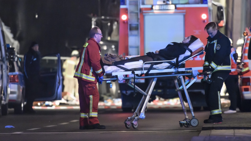 An injured person is carried on a stretcher by a firefighter at the scene [EPA]