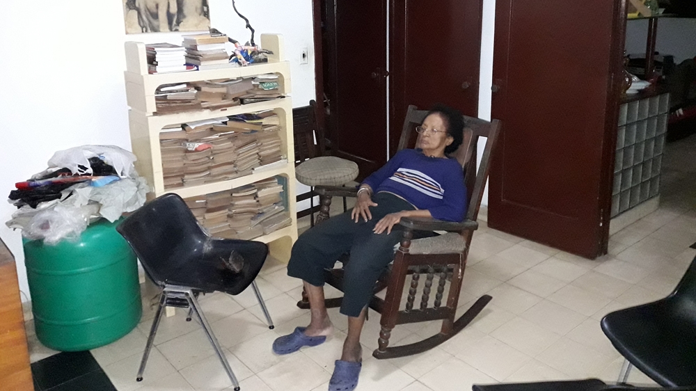 Elena Rodríguez watches TV at her neighbour's house [Abraham Jimenez Enoa/Al Jazeera] 