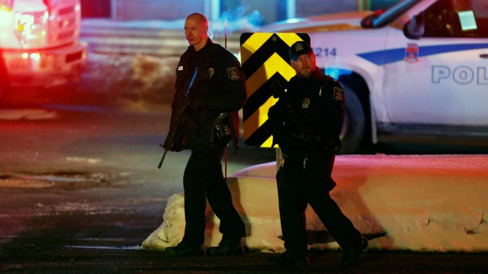 Police officers patrol the perimeter near a mosque after a shooting in Quebec City