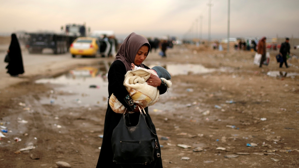A displaced Iraqi woman carries her baby after fleeing the battle between Iraqi rapid response forces and Islamic State militants near Mosul