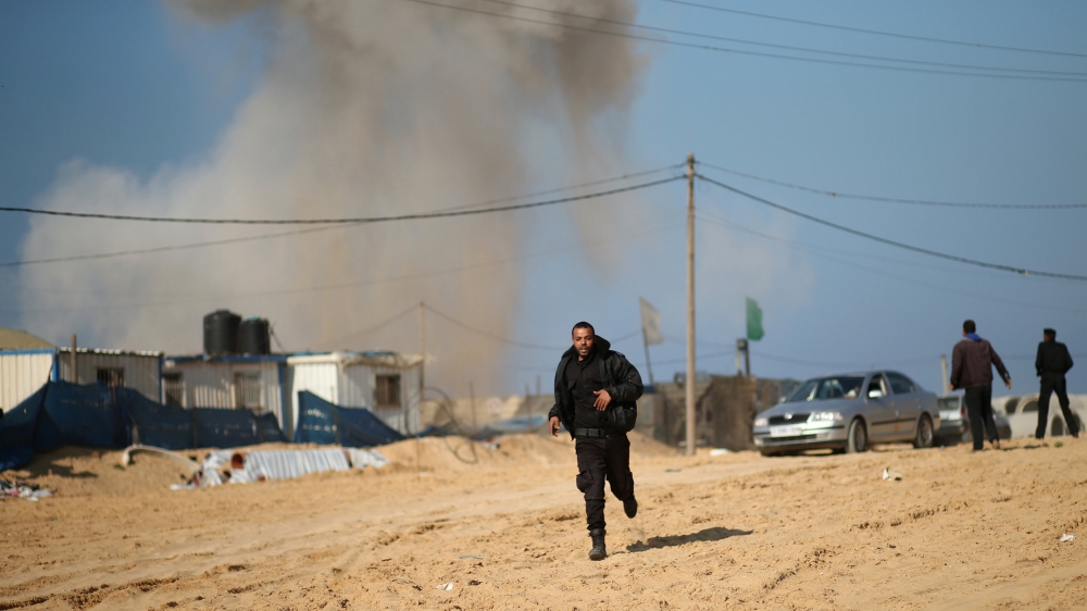 Palestinian security officer runs as smoke rises following what police said was an Israeli air strike on a Hamas post, in the northern Gaza Strip