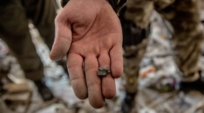 A police officer shows the piece of shrapnel in destroyed house. 'From my experience, it looks like the element of 122mm shell,' he says [Anton Skyba/Al Jazeera]